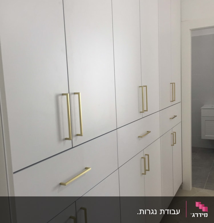 ארונות לבנים עם ידיות זהב מותקנים בקיר